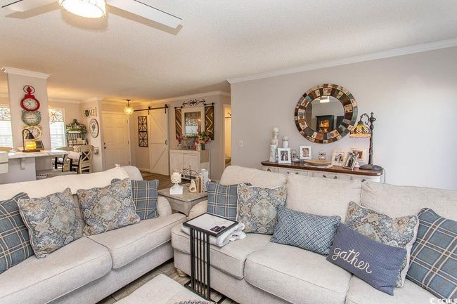 Living area featuring a barn door, ornamental molding, a ceiling fan, and a textured ceiling | Image 20