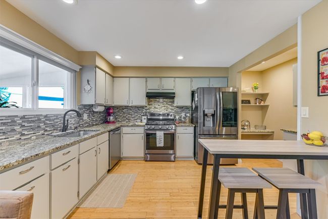 The kitchen shines with granite countertops, tile backsplash, and stainless steel appliances that add a modern edge | Image 5