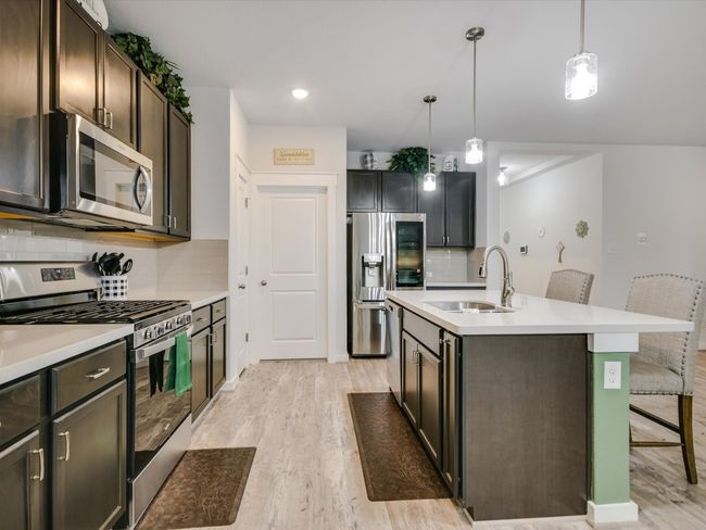 The Kitchen Appliances are stainless, including the dishwasher, Gas Freestanding Range & Microwave. The Refrigerator, Washer & Dryer are negotiable. - The door to the left is the tiled laundry room. It then connects to the Primary walk through closet! I really appreciate this design aspect! The Luxury Vinyl is in the main living, kitchen dining room& entry areas. | Image 6