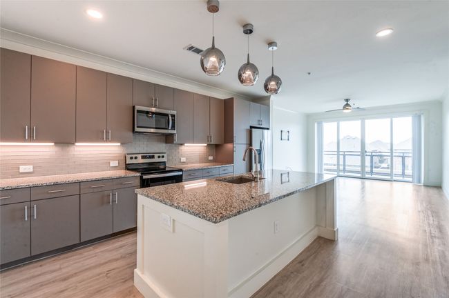 Kitchen featuring stainless steel appliances, light wood finished floors, tasteful backsplash, ceiling fan, and light stone countertops | Image 8