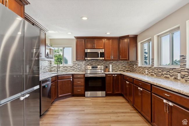 Kitchen with appliances with stainless steel finishes, granite countertops, wood LVP floors, recessed lighting, windows and backsplash | Image 10