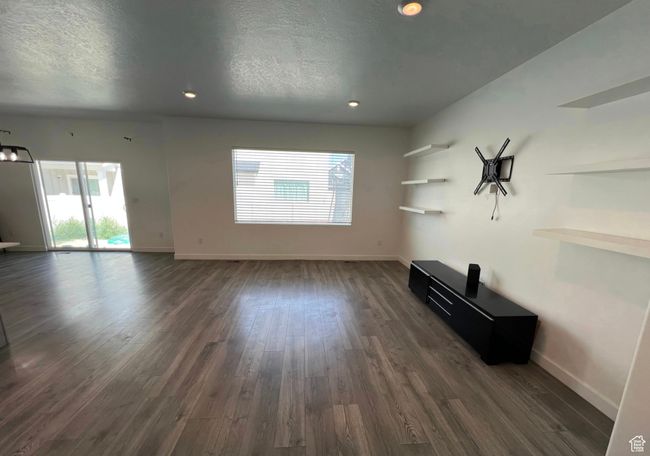 Unfurnished living room featuring dark wood-style floors, a textured ceiling, and recessed lighting | Image 4