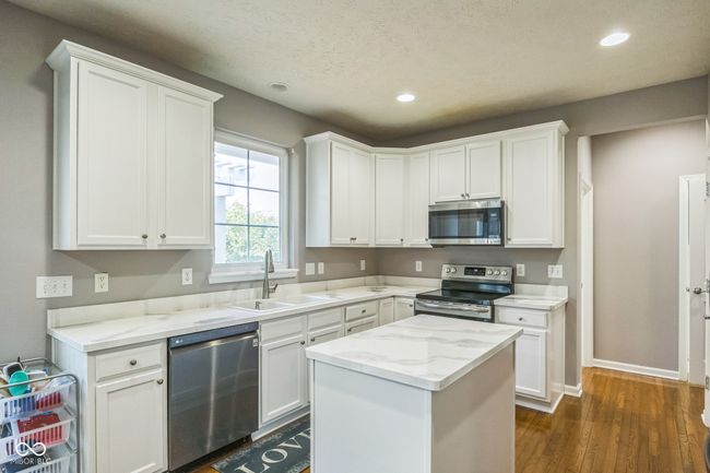 kitchen featuring appliances with stainless steel finishes, recessed lighting, white cabinetry, dark wood-style flooring, and light stone counters | Image 13