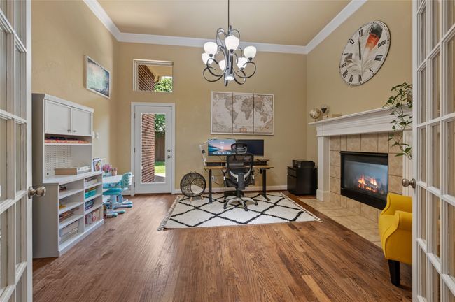 Office space featuring wood finished floors, crown molding, a fireplace, a chandelier, and french doors | Image 8