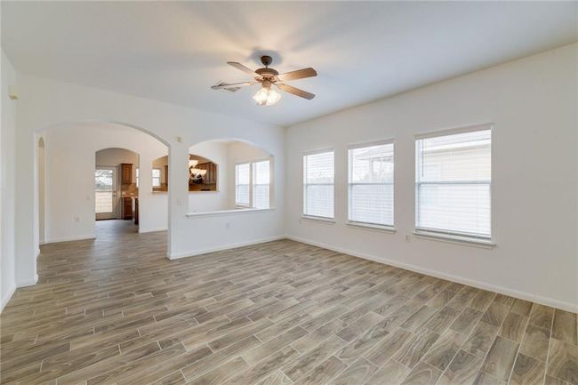 Unfurnished living room featuring ceiling fan, arched walkways, light wood-type flooring, and baseboards | Image 4
