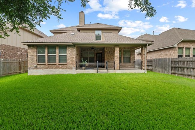 Rear view of property featuring a ceiling fan, a fenced backyard, a chimney, and brick siding | Image 40