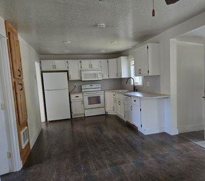 Kitchen with white appliances, dark wood-type flooring, and white cabinets | Image 3