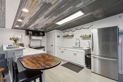 Kitchen with white cabinets, stainless steel refrigerator, sink, and light hardwood / wood-style floors | Image 2