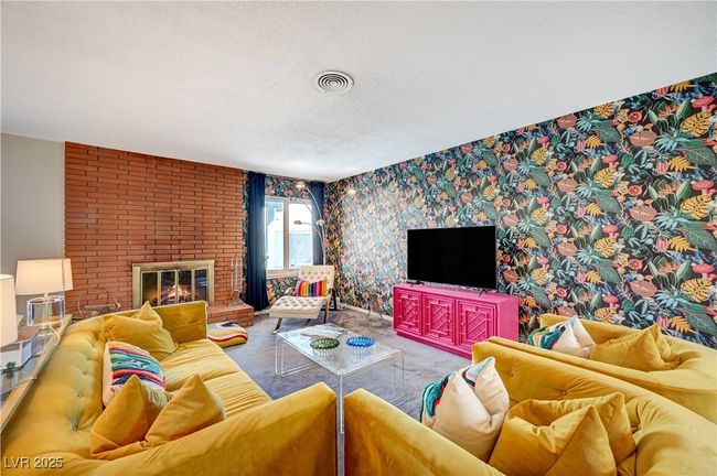 Living area with wallpapered walls, visible vents, a textured ceiling, carpet floors, and a brick fireplace | Image 6