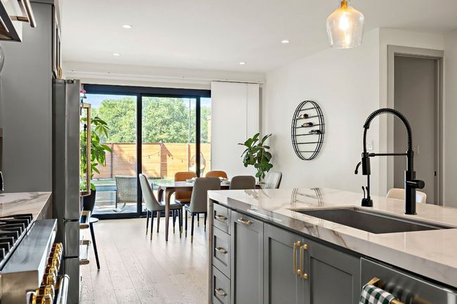 Kitchen with gray cabinetry, light wood-style flooring, light stone counters, and a sink | Image 8