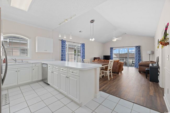 Kitchen featuring open floor plan, light tile patterned flooring, appliances with stainless steel finishes, a ceiling fan, and vaulted ceiling | Image 6