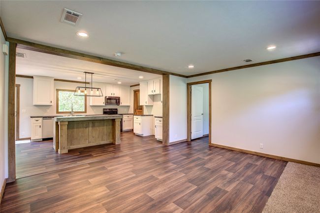 Kitchen with stainless steel appliances, dark countertops, white cabinetry, dark wood-style flooring, and ornamental molding | Image 9