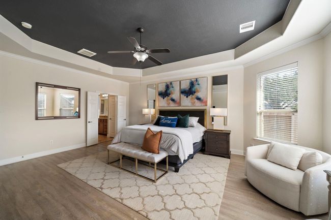 This elegant primary bedroom features a tray ceiling and refined details, showcasing an ideal retreat within the home. Abundant natural light fills the room, enhancing its spacious feel and comfortable ambiance. | Image 29