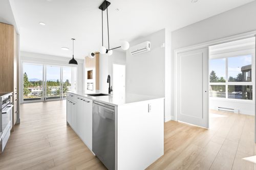 Contemporary kitchen island featuring a stainless steel dishwasher, undermount sink with a matte black faucet, and white countertops | Card Image