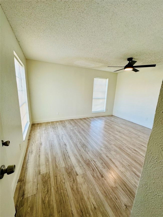 Unfurnished room with wood finished floors, a textured ceiling, a ceiling fan, and baseboards | Image 10