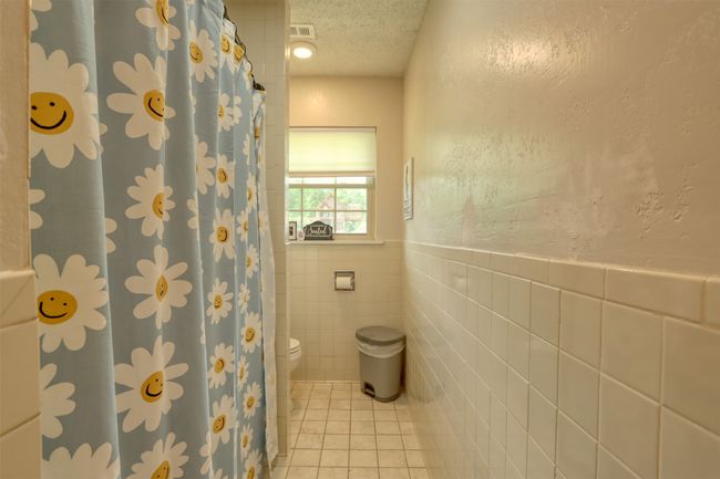 Full bath with tile walls, tile patterned flooring, a textured ceiling, wainscoting, and a shower with curtain | Image 29