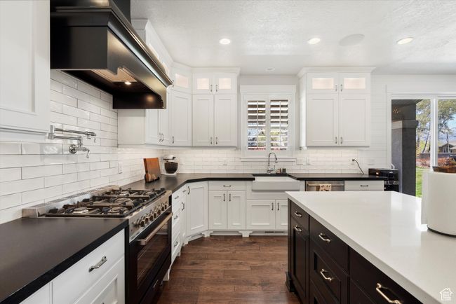 Kitchen featuring high end range, white cabinets, a sink, premium range hood, and backsplash | Image 17