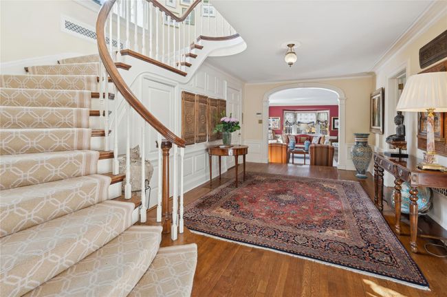 Foyer featuring arched walkways, a wainscoted wall, a decorative wall, ornamental molding, and hardwood / wood-style flooring | Image 19
