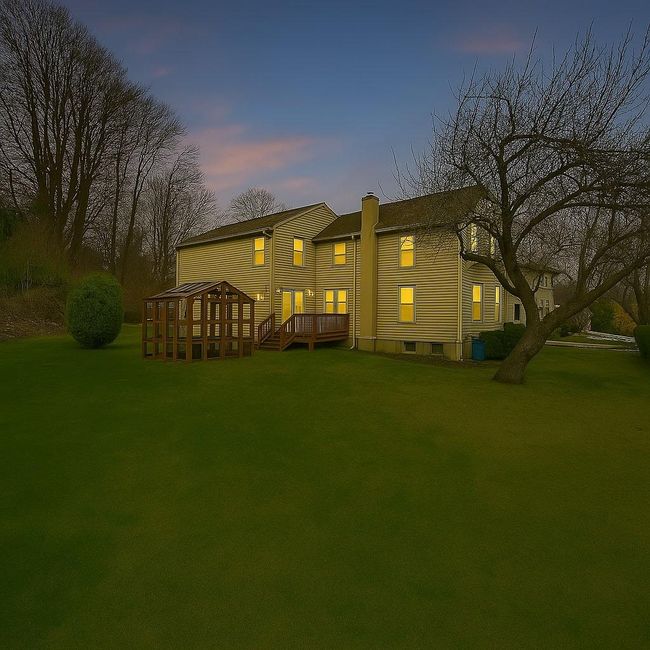 Side of house at dusk with a chimney, a deck, and a lawn. Digitally enhanced | Image 5