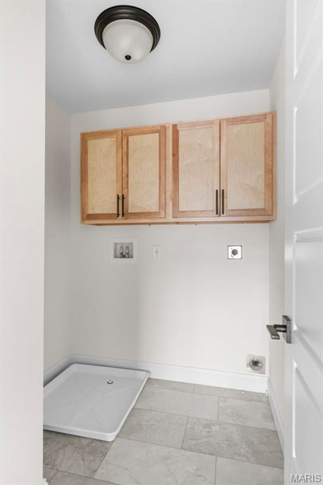 Laundry area featuring electric dryer hookup, cabinet space, washer hookup, and light marble finish floors | Image 14
