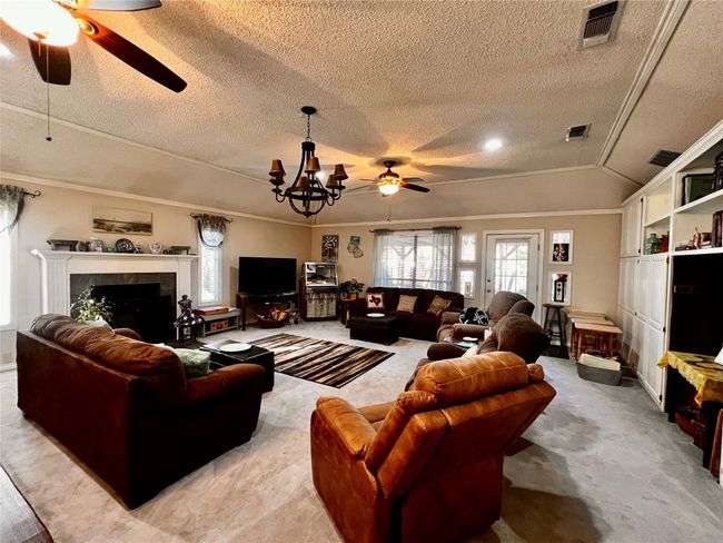 Living room featuring a textured ceiling, ornamental molding, and a tiled fireplace | Image 14