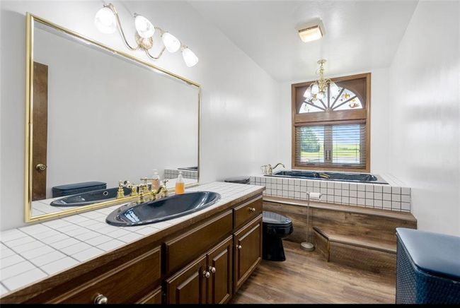 Bathroom featuring an inviting chandelier, wood finished floors, toilet, and vanity | Image 15