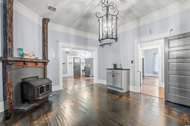 Living area featuring a wood stove, dark wood-style floors, crown molding, and a chandelier | Image 8