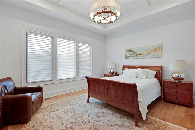 Bedroom featuring baseboards, a chandelier, wood finished floors, and visible vents | Image 32