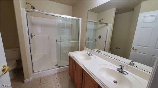 Full bath featuring toilet, a sink, tile patterned floors, and a shower stall | Image 12