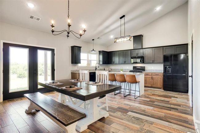 Dining area featuring high vaulted ceiling, french doors, a notable chandelier, and wood-type flooring | Image 10