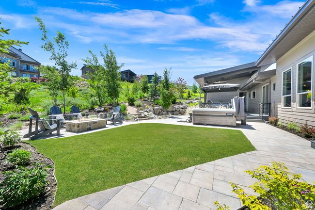 View of green lawn featuring a patio area, an outdoor fire pit, and a hot tub | Image 64