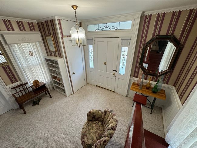 Foyer entrance with wallpapered walls, a chandelier, crown molding, and carpet | Image 23