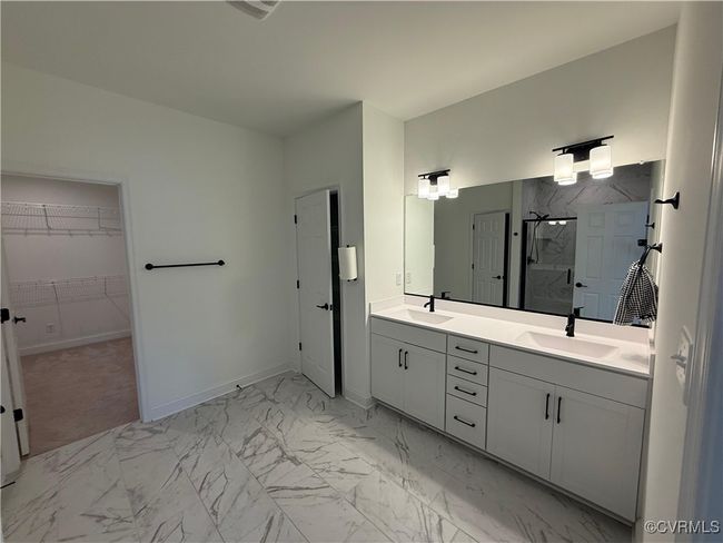 Bathroom featuring a marble finish shower, marble finish floors, double vanity, and a walk in closet | Image 6