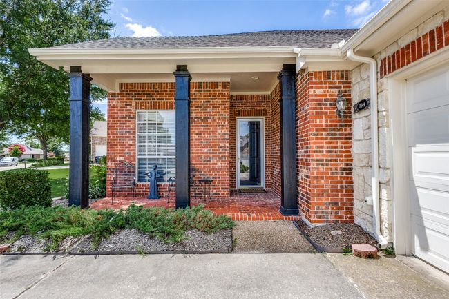 Doorway to property featuring brick siding, an attached garage, and roof with shingles | Image 4