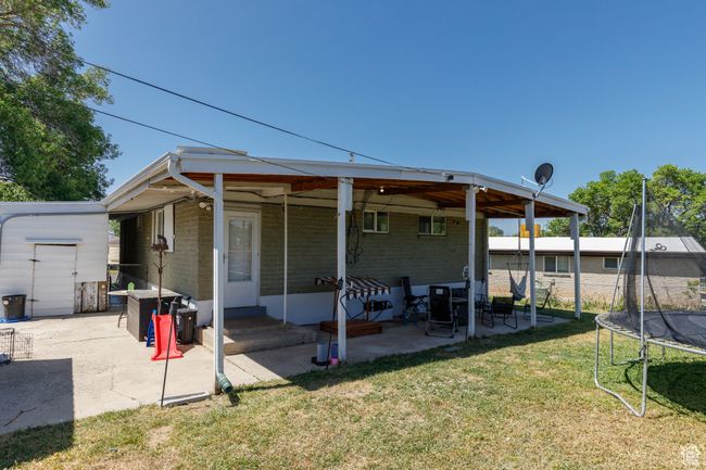 Rear view of property with a trampoline, a patio, a yard, brick siding, and a storage unit | Image 26