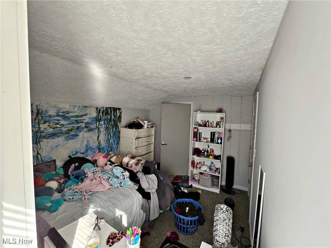 Bedroom featuring lofted ceiling, a textured ceiling, and carpet flooring | Image 44