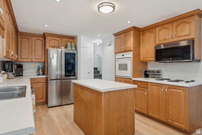 Kitchen with light countertops, a kitchen island, light wood-style floors, and appliances with stainless steel finishes | Image 9