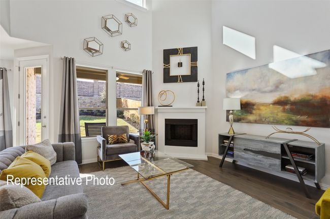 Living area featuring a fireplace with flush hearth, wood finished floors, a high ceiling, and a wealth of natural light | Image 6