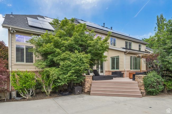 Rear view of house with roof mounted solar panels, brick siding, and a deck | Image 74