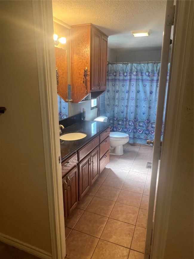 Full bath with tile patterned floors, vanity, a textured ceiling, and curtained shower | Image 15
