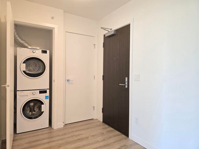 Laundry room with stacked washer / dryer and light wood-style floors | Image 15