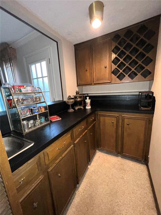 Elevate your entertaining with this stylish wet bar, featuring ample cabinetry, elegant countertops, and a built-in wine rack. Perfect for hosting and relaxing. | Image 6