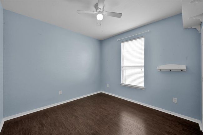 Soothing blue walls, a ceiling fan, and dark wood flooring. It includes a double-door closet with ample storage space above, providing functionality and style. | Image 25