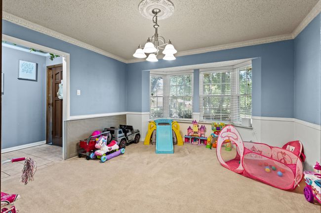 Rec room with ornamental molding, a chandelier, a textured ceiling, and carpet floors | Image 19