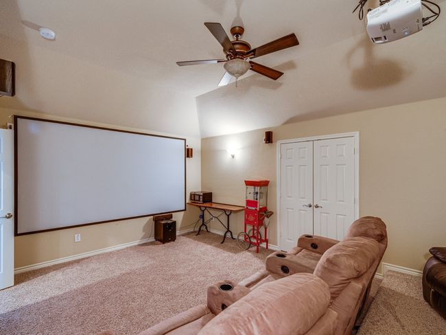 Cinema with carpet flooring, baseboards, a ceiling fan, and vaulted ceiling | Image 26