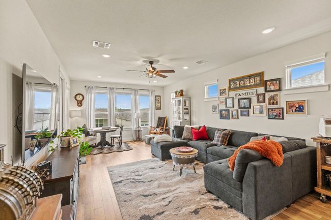 Living area with wood finished floors, visible vents, ceiling fan, and a healthy amount of sunlight | Image 13