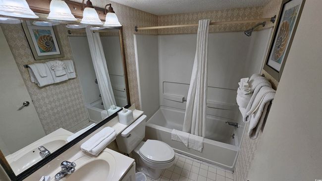 Bathroom featuring toilet, a textured ceiling, wallpapered walls, and shower / bathtub combination with curtain | Image 17