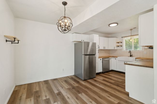 Kitchen featuring appliances with stainless steel finishes, a sink, dark wood finished floors, tasteful backsplash, and white cabinetry | Image 5