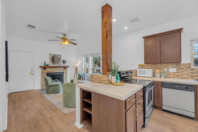Kitchen featuring dishwasher, stainless steel range with electric cooktop, white microwave, light wood-style floors, and recessed lighting | Image 15
