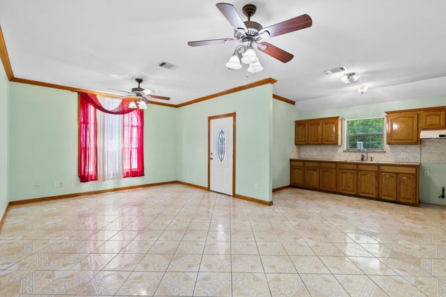 Unfurnished living room featuring crown molding, baseboards, ceiling fan, and a sink | Image 18